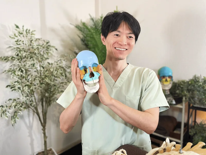 頭蓋骨模型を手に、笑顔で解説する講師の南克明