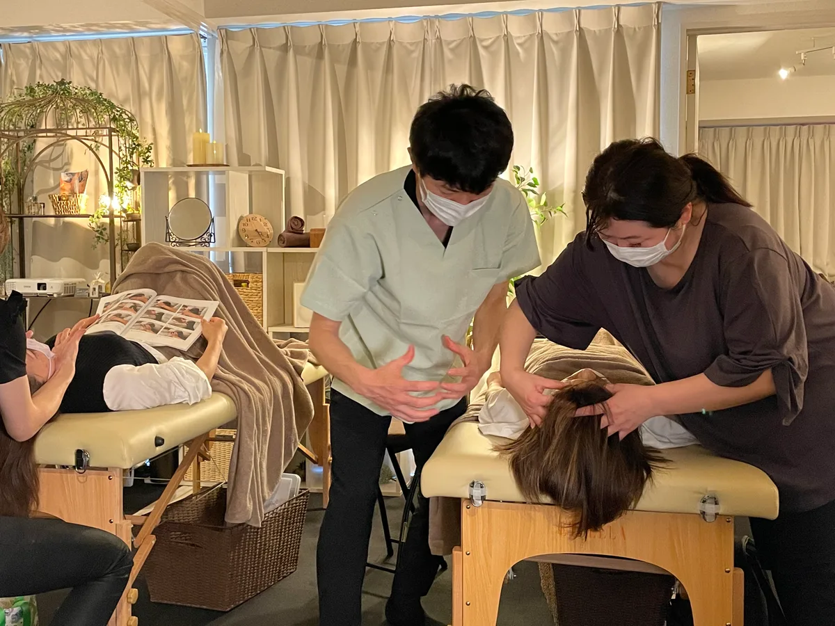 集合講座で、南が受講生のドライヘッドスパの練習を見ながら手の動きを伝える様子